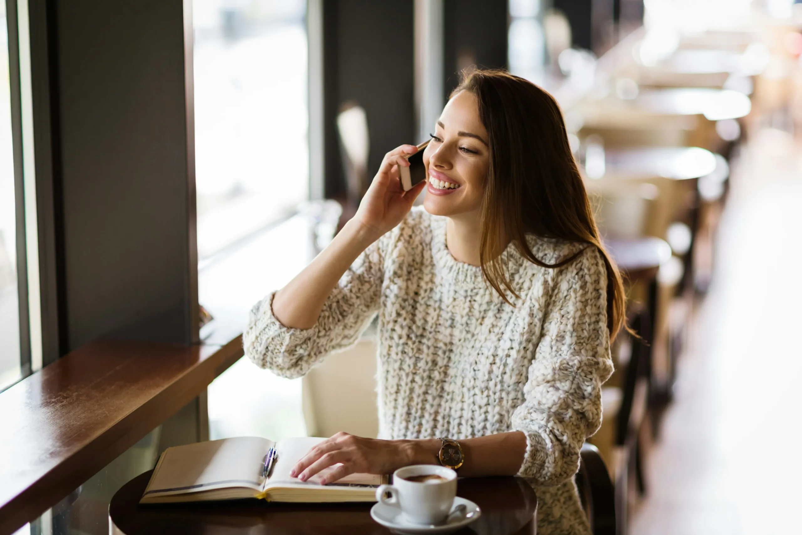 Utah Estate Tax Attorney Smiling girl is on phone call with her book & tea on her desk.